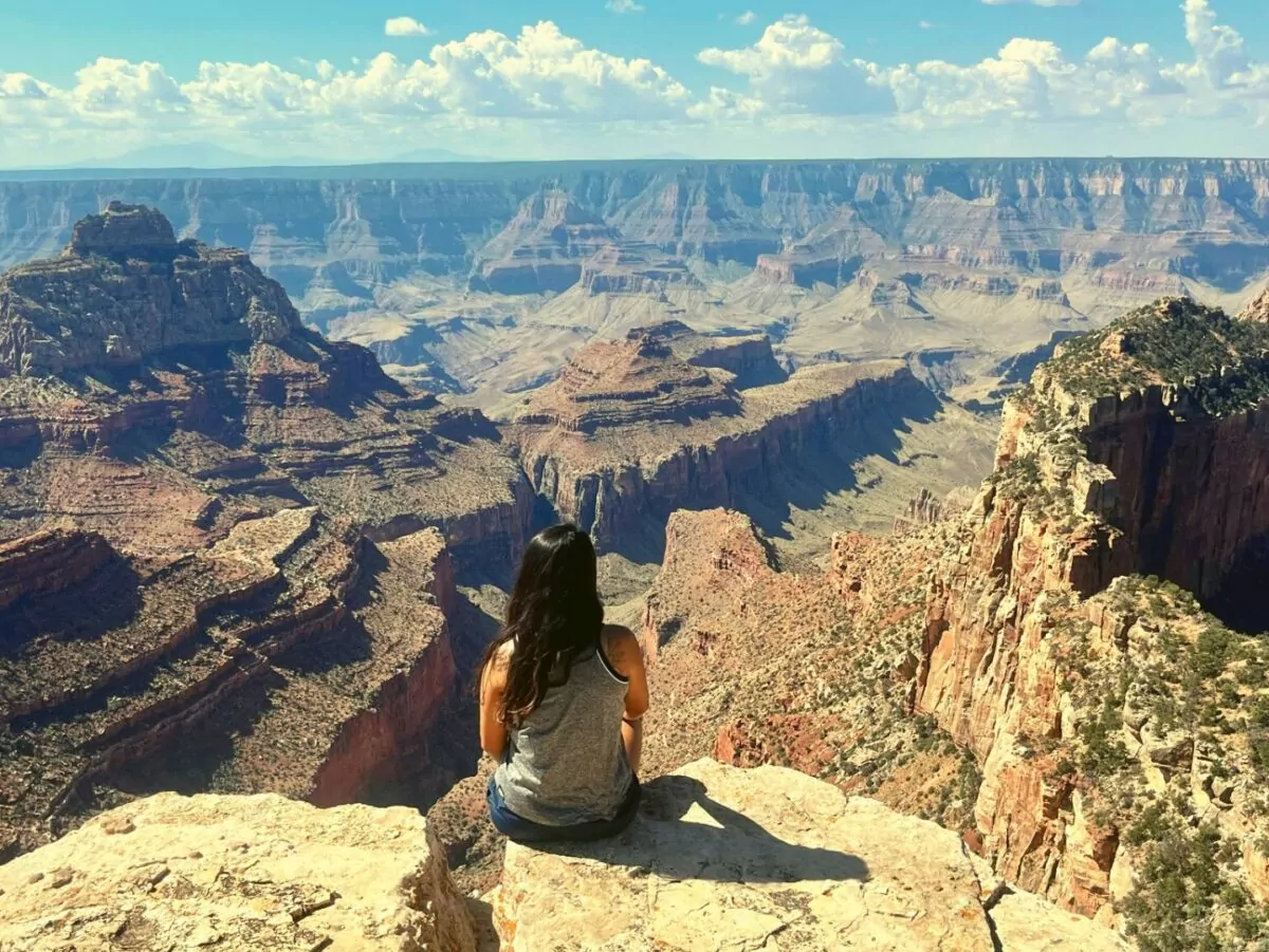 Solo female traveler sits on the edge of the Grand Canyon
