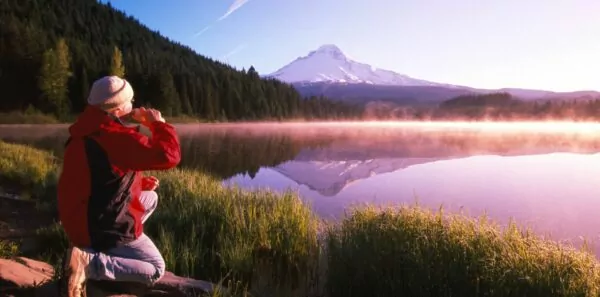 Person perches next to Mirror Lake below Mount Hood