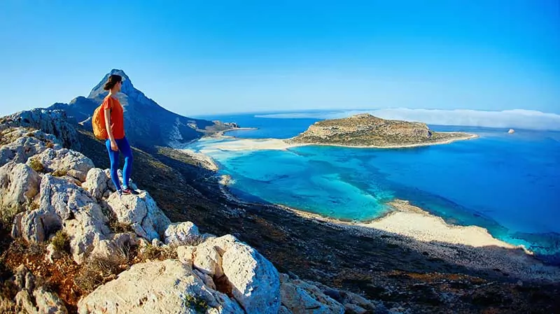 panoramic view on Balos beach, Crete, Greece. Woman, traveller stands on the cliff against sea background