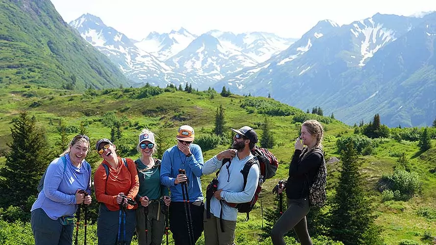 Wildland Trekking group celebrating with glaciers and mountains views behind them