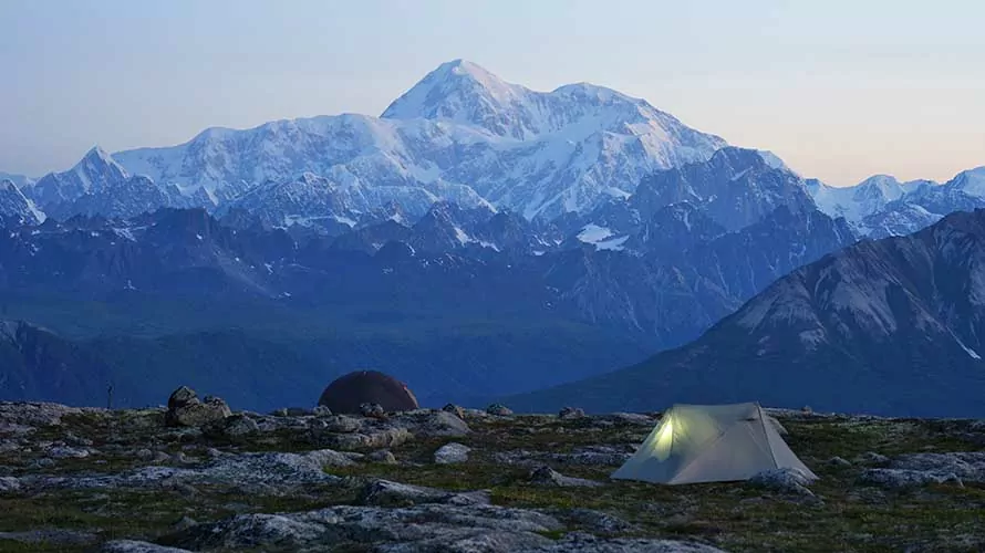 Headlamp in tent with Denali in background, Alaska