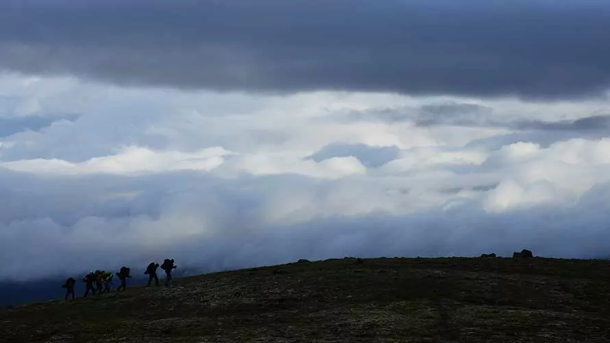 Backpackers hiking in front of low cloud bank, Alaska