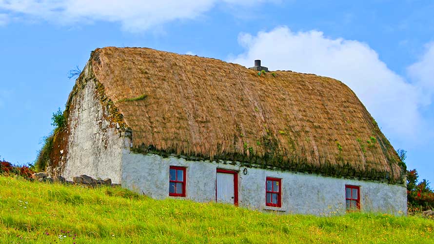Classical thatched Irish cottage with green grass upon a blue sky. The photo was taken in Inis Mor