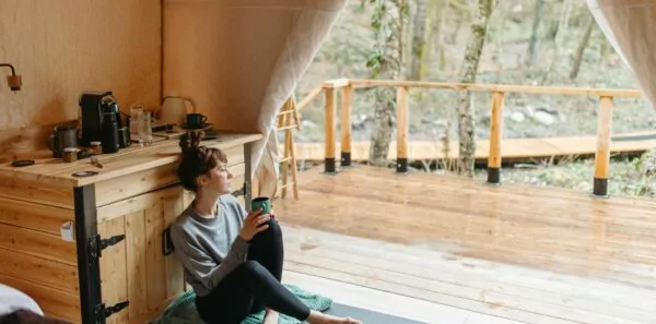 A woman sits inside a rustic yurt looking outside