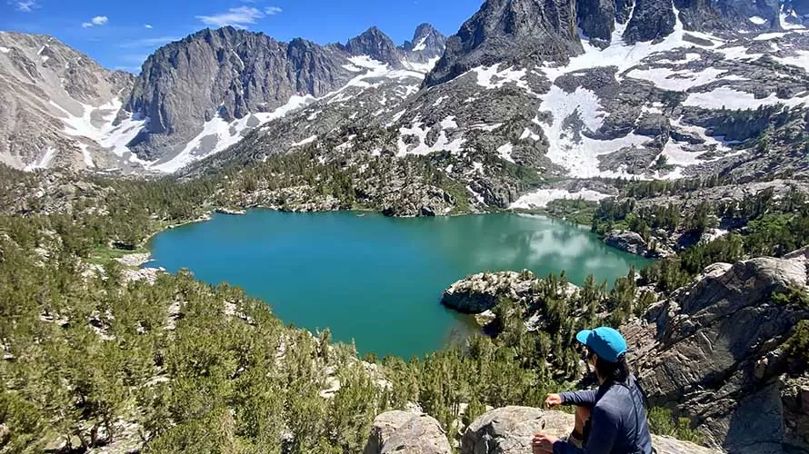 Woman looking out over an alpine lake and mountains on the John Muir Trail