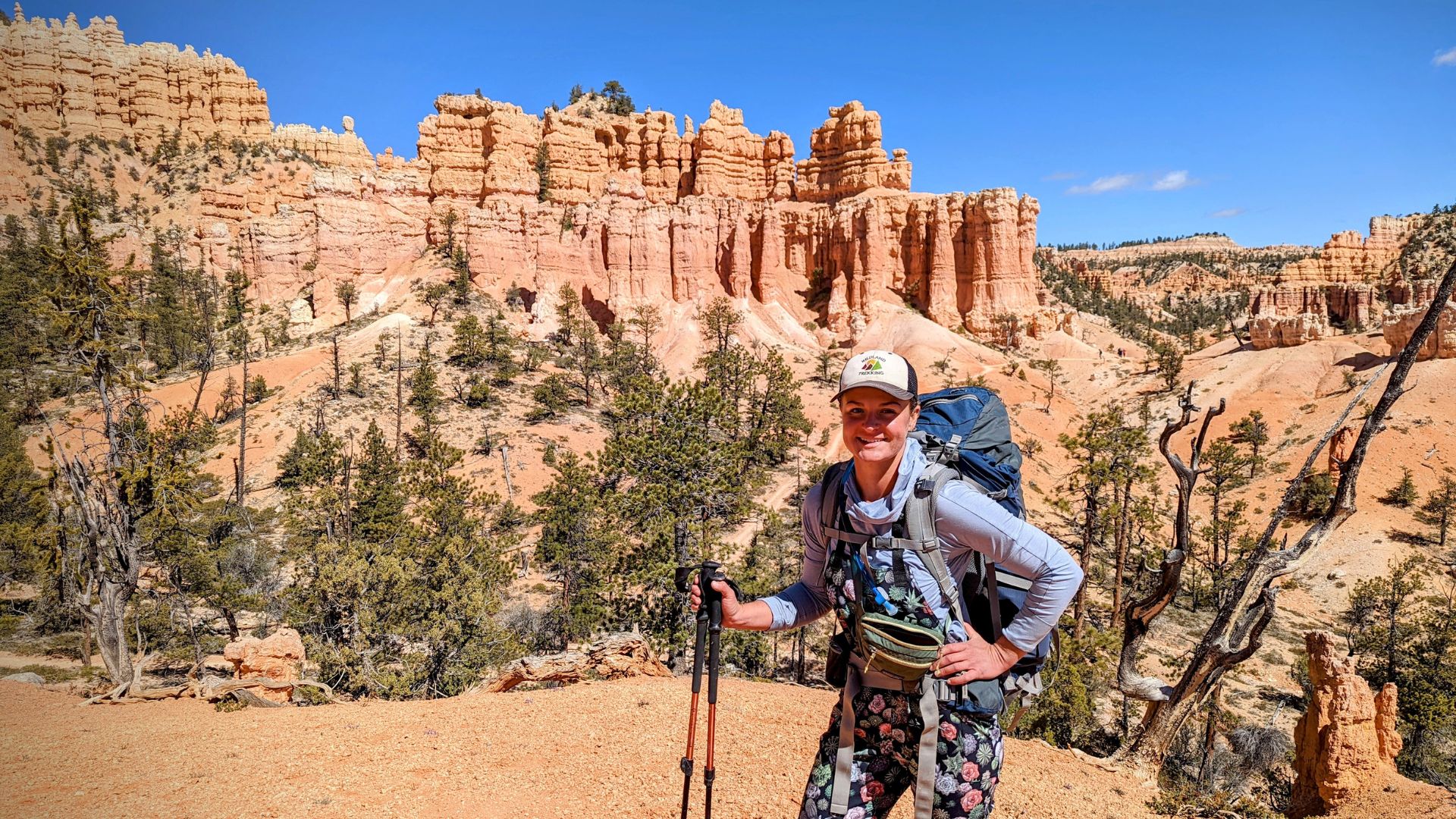 A hiker outfitted for a day in the desert stands in front of Bryce Canyon National Park hoodoos