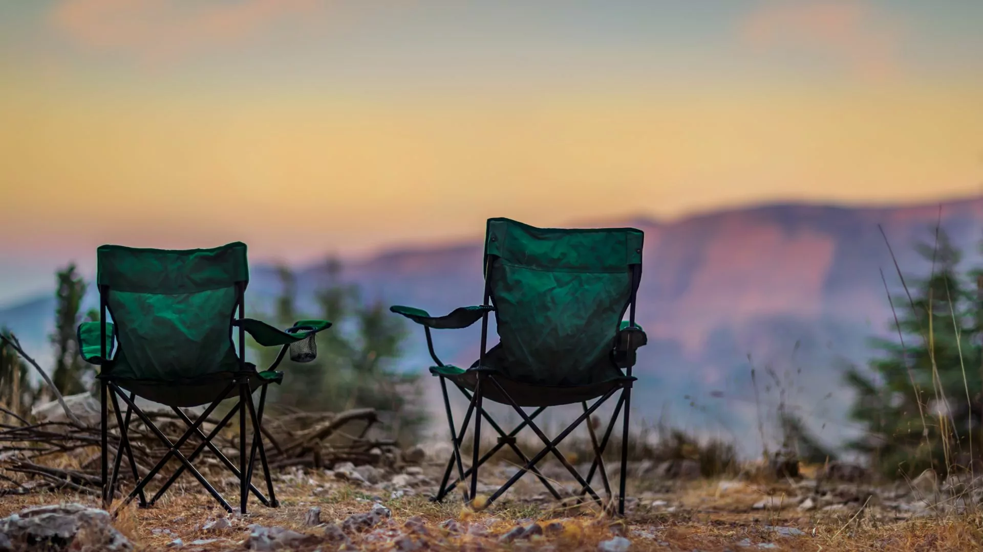 Two camp chairs stand with a sunrise view behind