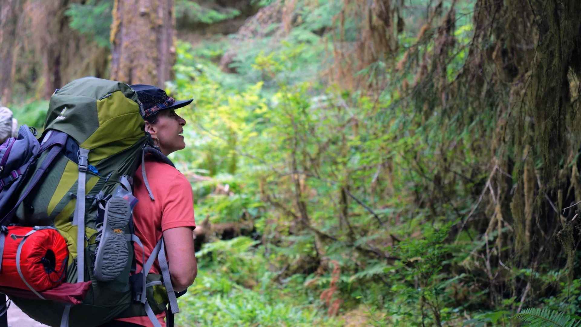 A woman with a backpack heads into the rainforest ready for multiple days outdoors