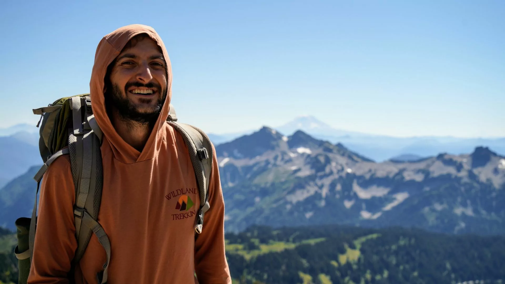 A Wildland Trekking hiking and backpacking guide smiles with mountains of the Pacific Northwest behind him