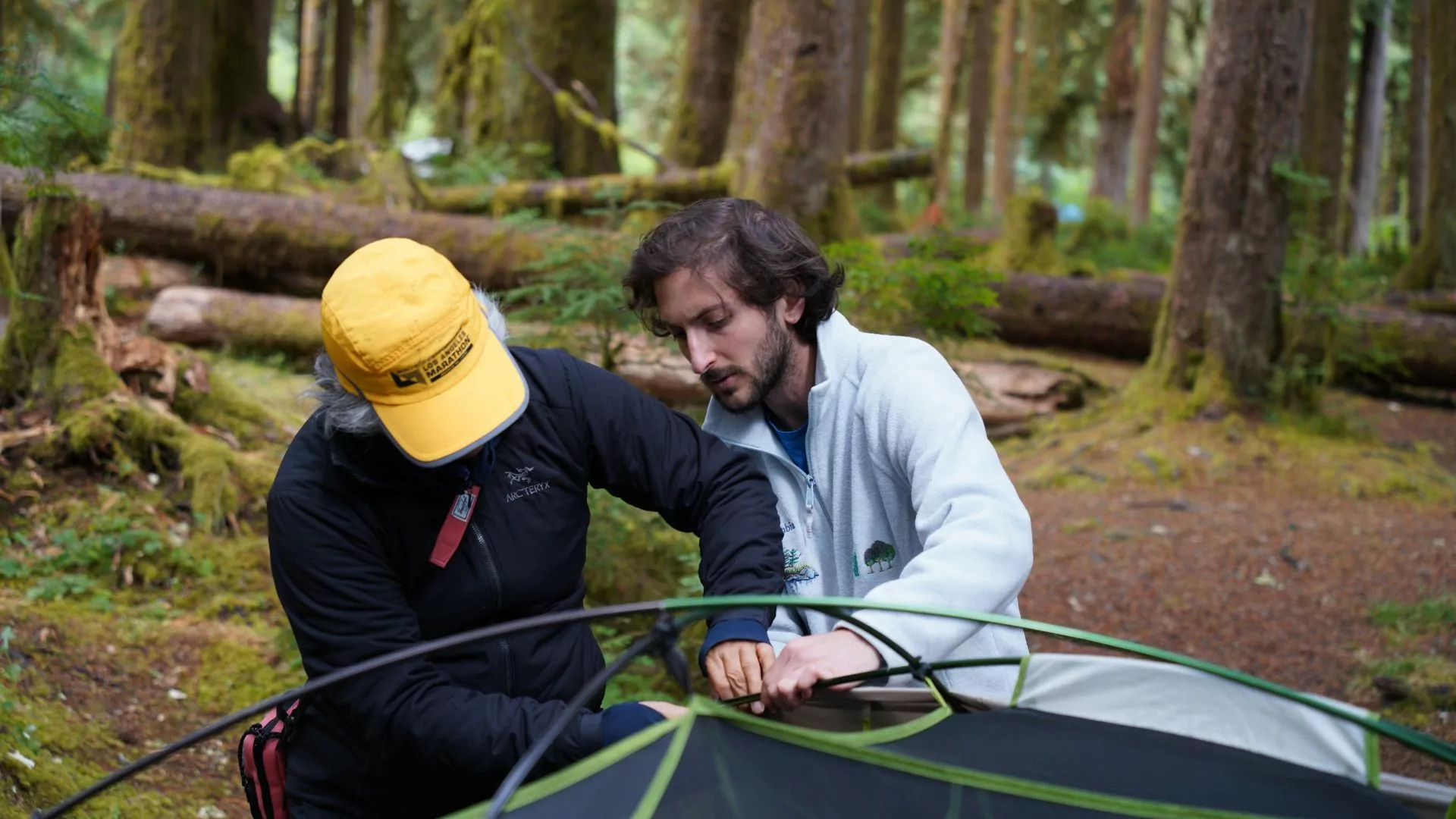 A hiking guide helps his guest set up a tent