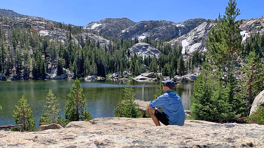 Lone hiker soaking up the majesty of nature near a lake in the Sierra Nevada, California