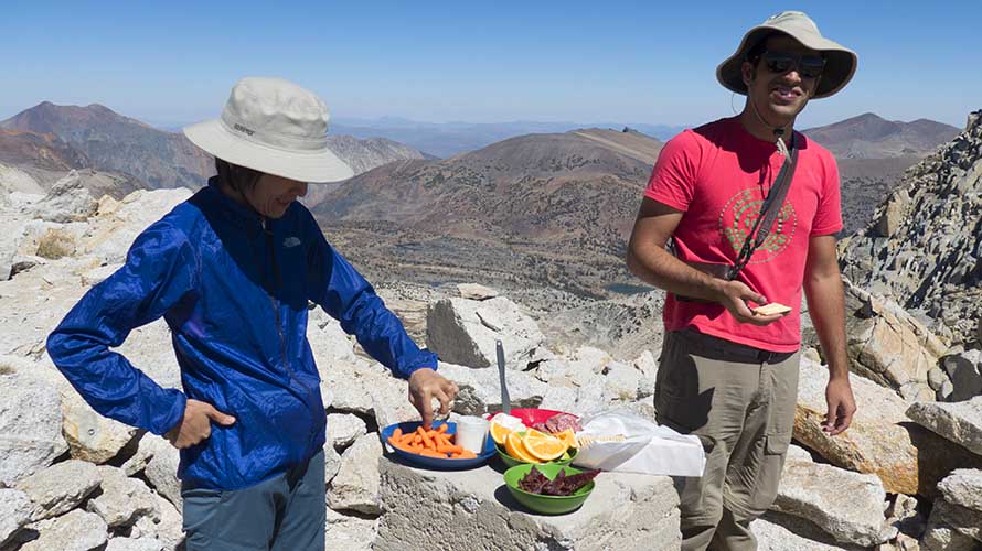 Two hikers eating lunch atop an alpine peak in the Sierra Nevada Mountains