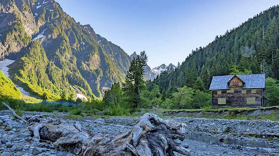 The Quinault River flowing through the braided riverbank within Enchanted Valley in Olympic National Park, past the historic chalet cabin, at sunrise.