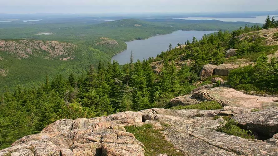 Hikers ascending Pemetic Mountain from the south can gaze north across Eagle Lake on Mount Desert Island to distant Frenchman Bay and Lamoine, a town in Hancock County. Pemetic Mountain rises in Acadia National Park.