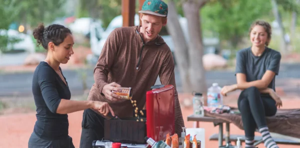 Friends cook a vegan meal outside on a camp stove