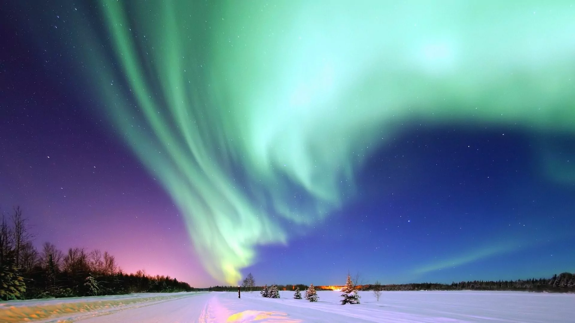 Colorful northern lights dance across the winter night sky in snowy Alaska