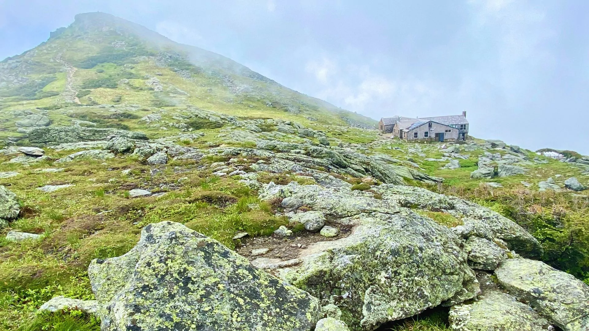 Lake of the clouds hut perches on the side of a mountain in the mist