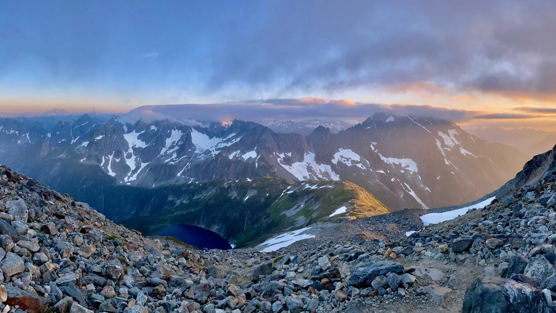 An alpine lake lies among a multitude of mountain peaks