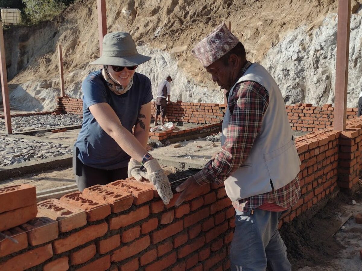 An American volunteer helps construct a masonry foundation in Nepal