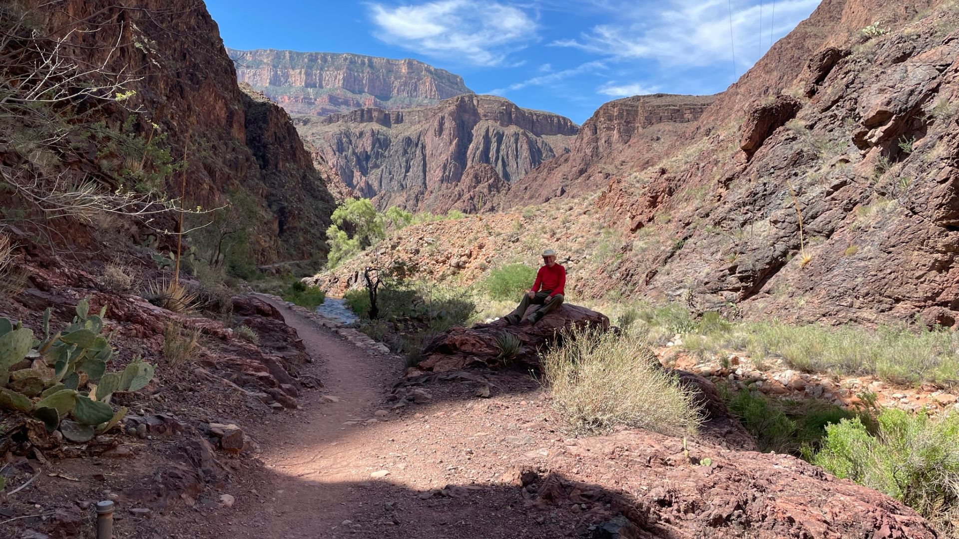 A hiker rests in the shade at the bottom of the Grand Canyon