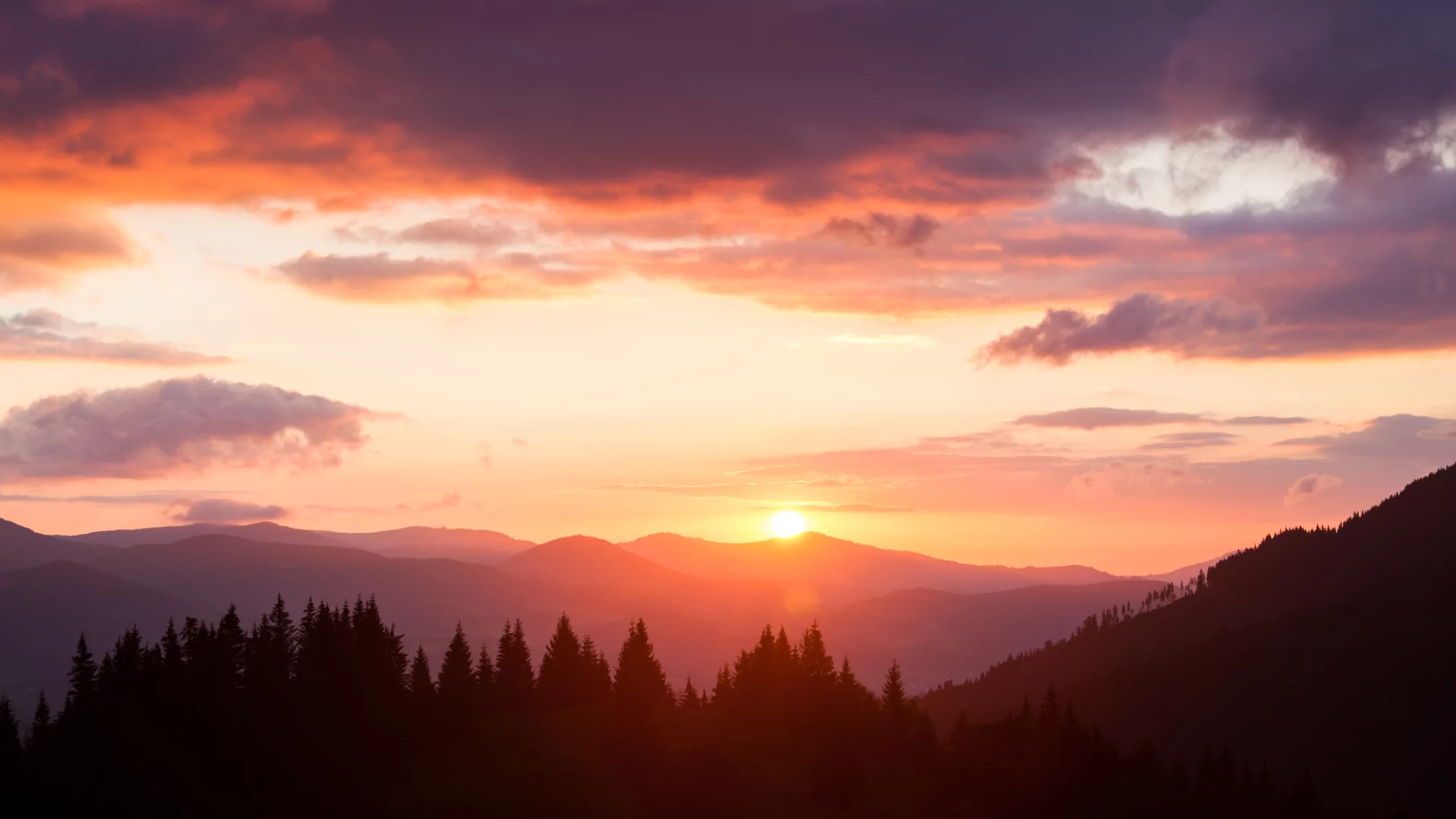 A warm red gold glow lights the sky and the forests of the smokey mountains below