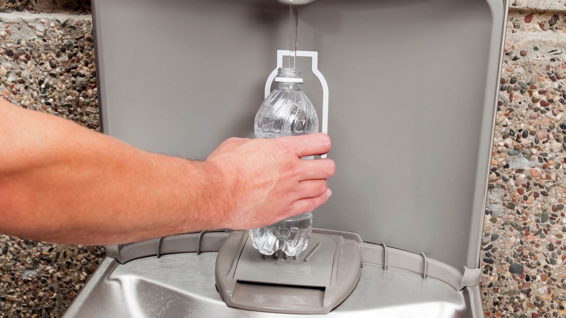 Someone fills a water bottle at a water fountain