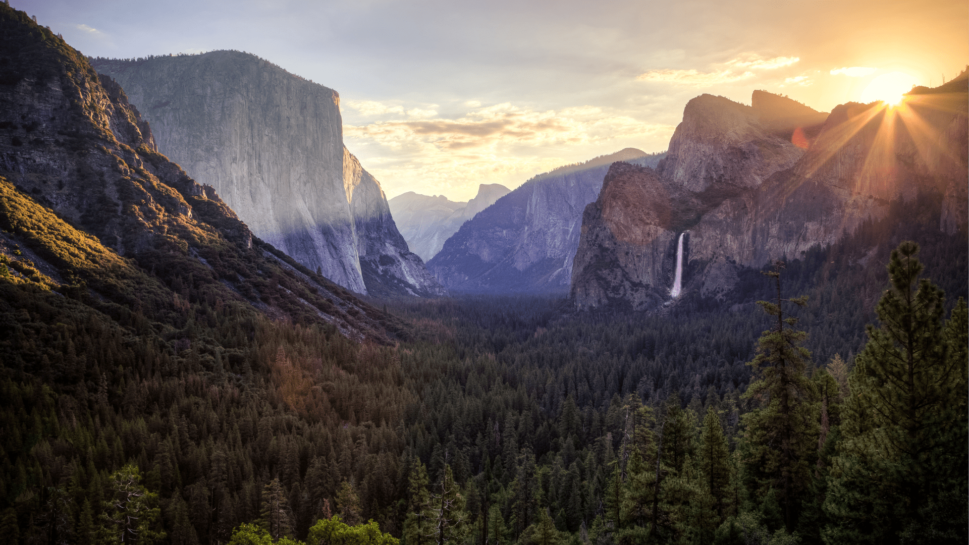 Light spills into Yosemite valley as the sun rise starts to crest above high granite walls