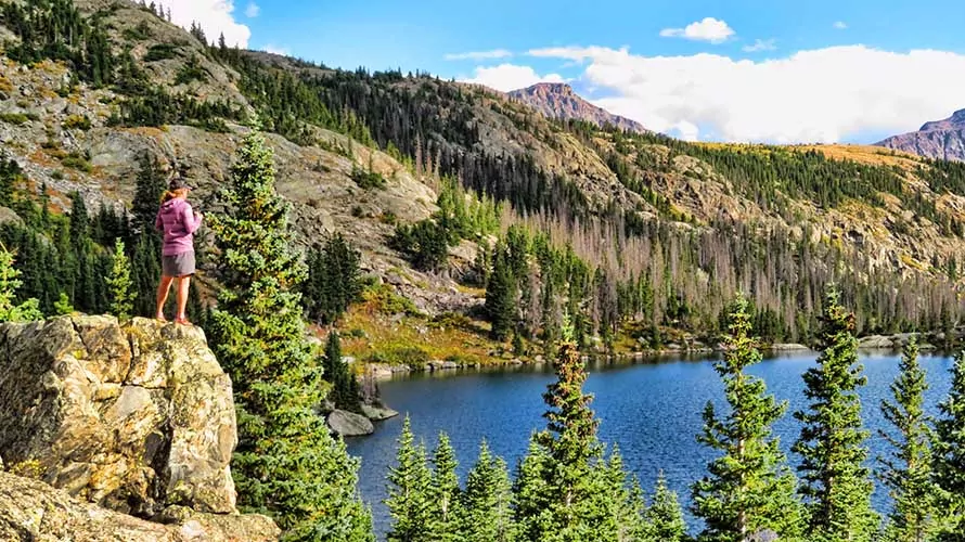 Woman standing on rock above an alpine lake in the Flat Tops Wilderness, Colorado