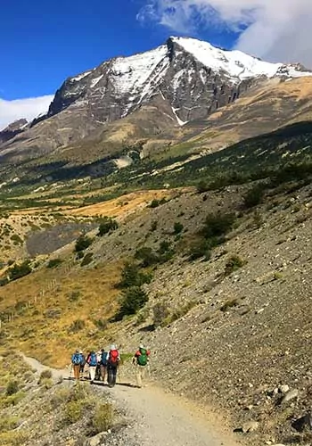 Hikers below snow-capped peaks in Torres del Paine National Park, Chile