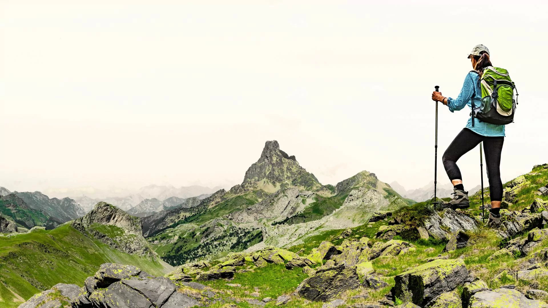 A hiker with a day pack and trekking poles stands ready to explore the Pyrenees