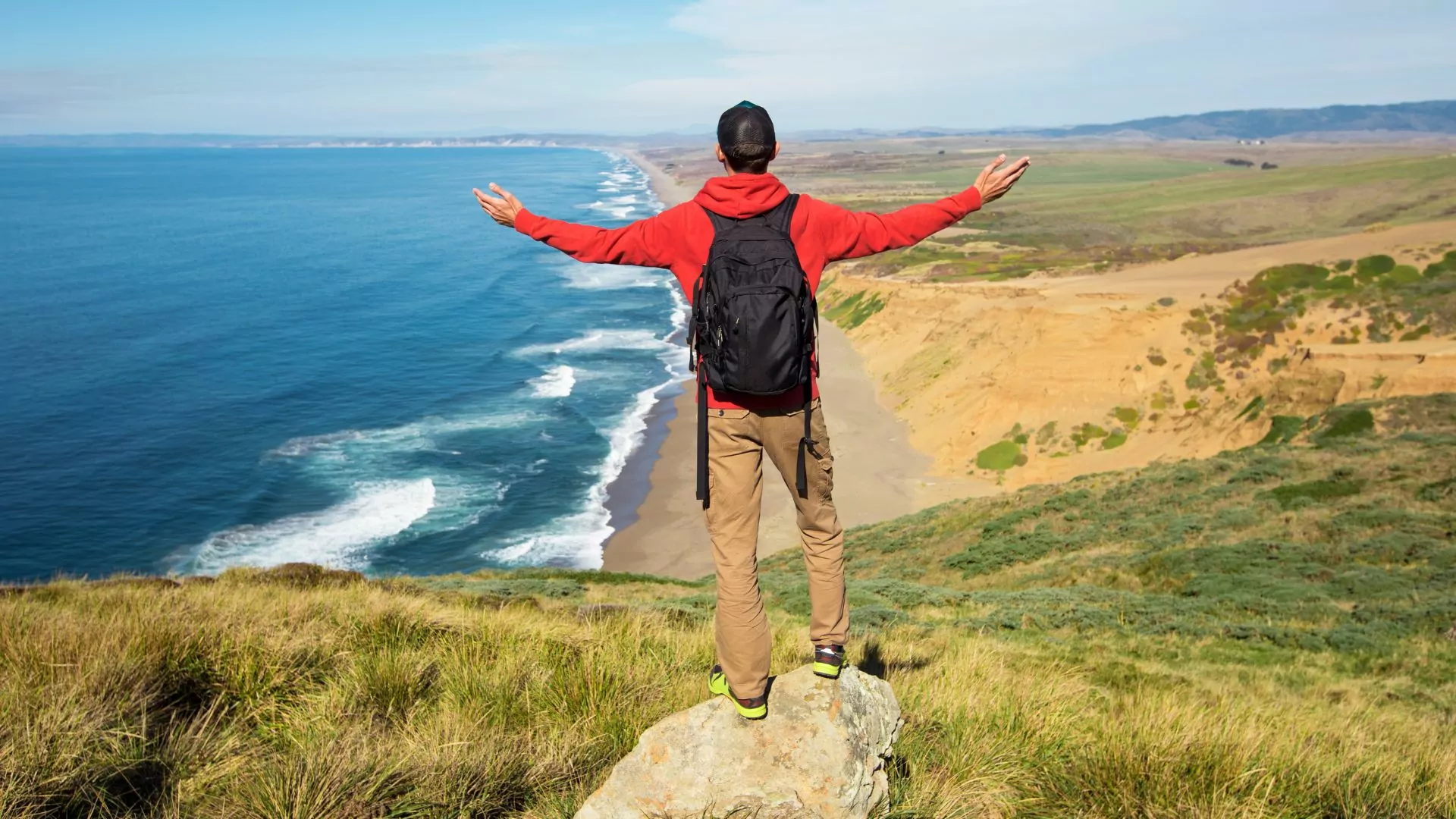 A visitor stands with arms wide taking in the view of Point Reyes National Seashore