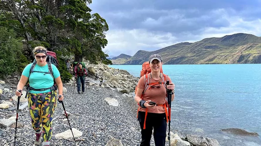 Hikers on gravel beach of turquoise lake in Torres del Paine, Chile