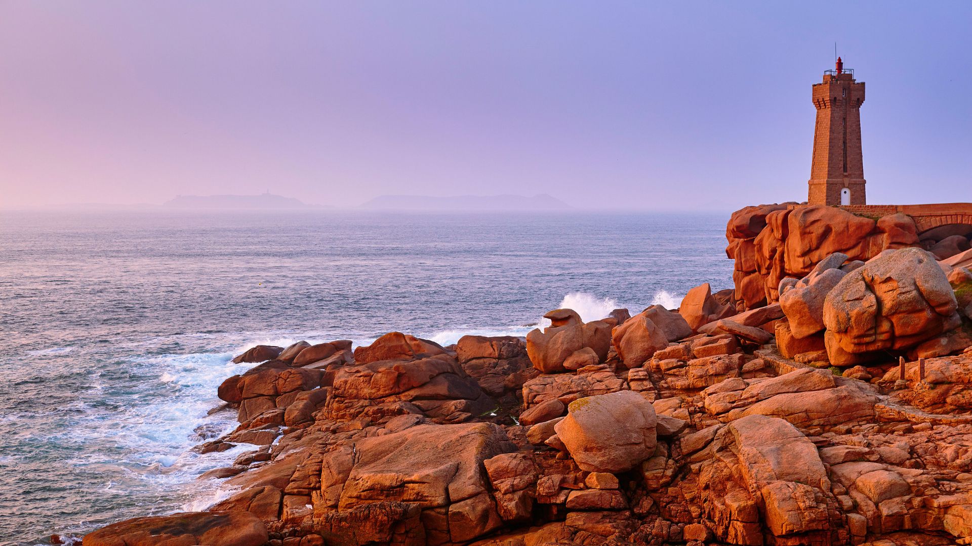 The sun sets on a rocky coastline of pink granite 