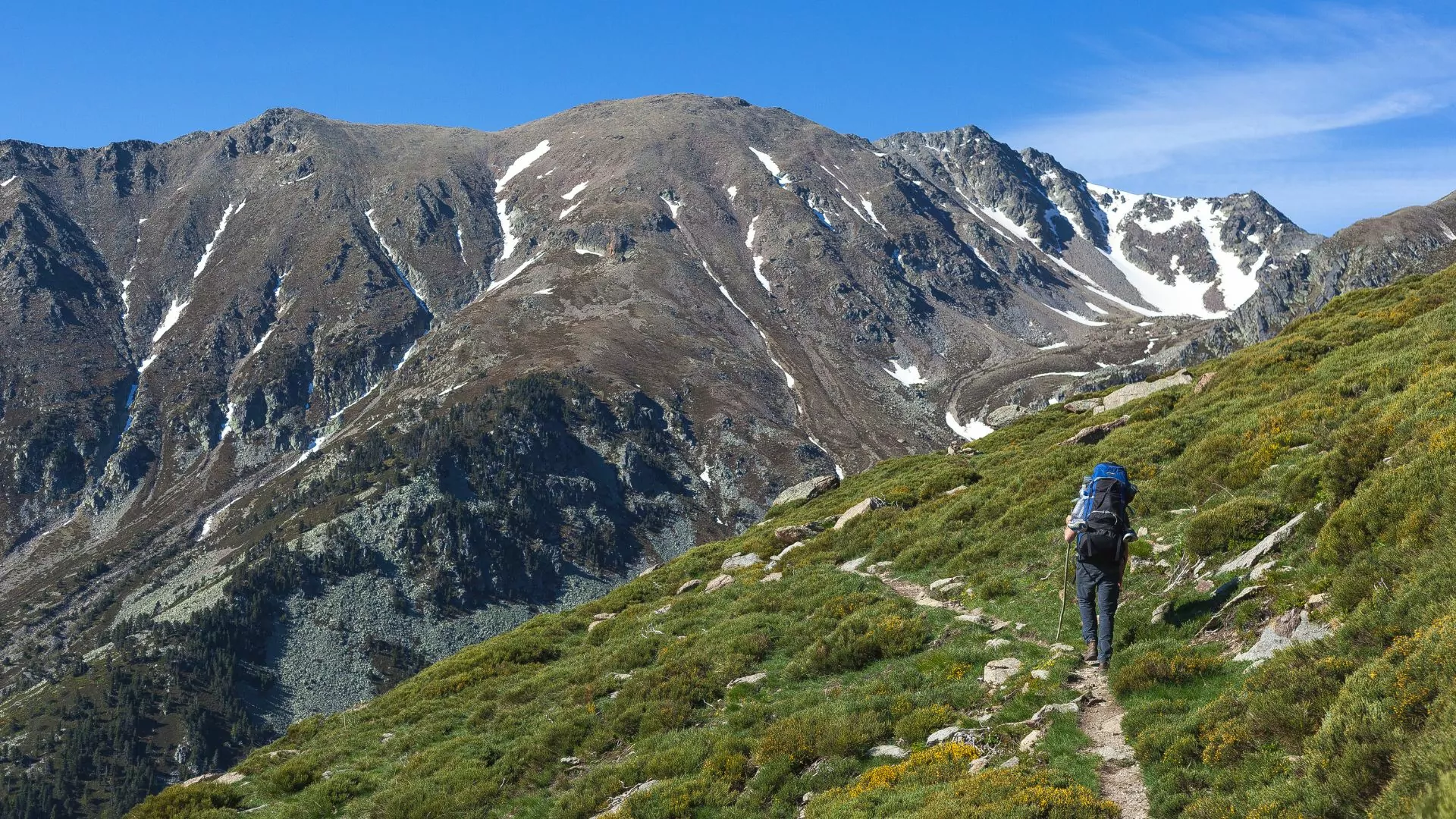 A backpacker follows a trail into the Pyrenees mountains