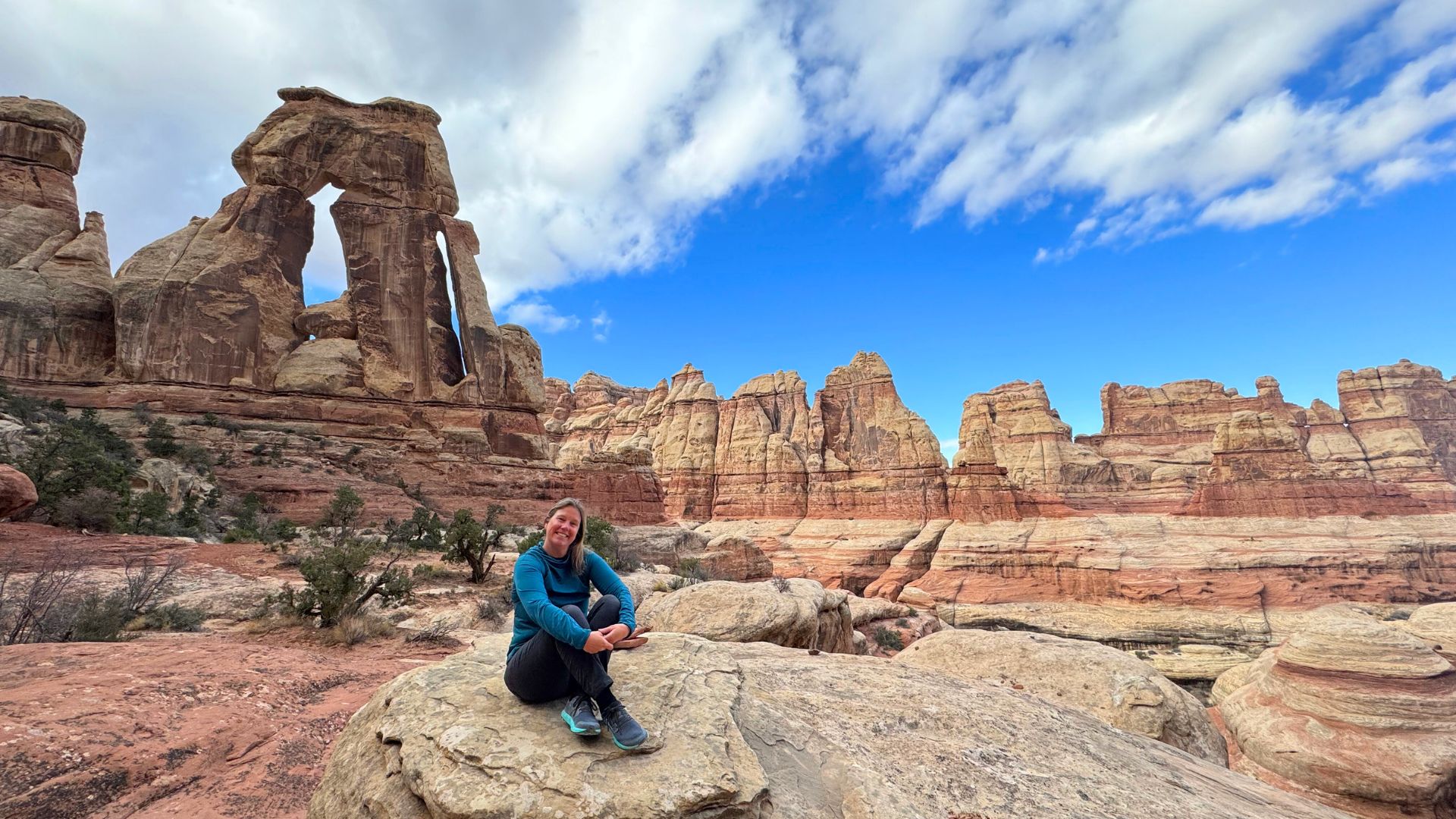 A woman sits in front of a backdrop of sandstone spires