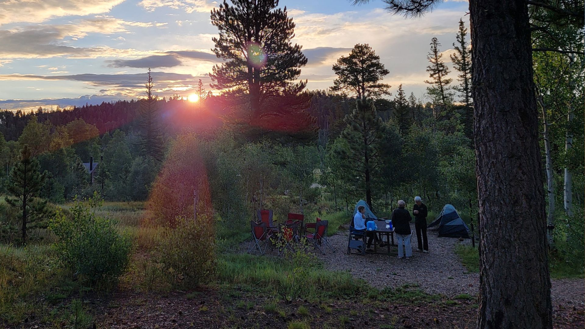 Hikers gather in a campsite as the sun sets