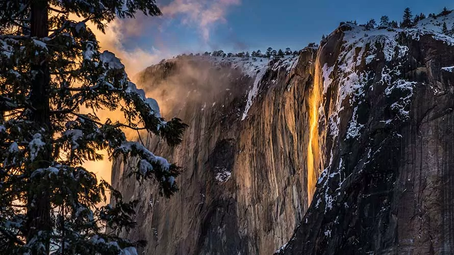 In the crisp embrace of February, this awe-inspiring photograph immortalizes the breathtaking spectacle of Yosemite's legendary firefall. As the sun dips below the horizon, a cascading ribbon of molten hues ignites the granite cliffs, casting the entire landscape aglow. The juxtaposition of wintry surroundings with the vivid, fiery cascade creates a mesmerizing portrait of nature at its most dramatic and enchanting, offering a fleeting glimpse of a truly magical moment.