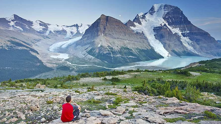 Hiker sitting looking at Berg Lake and Mount Robson