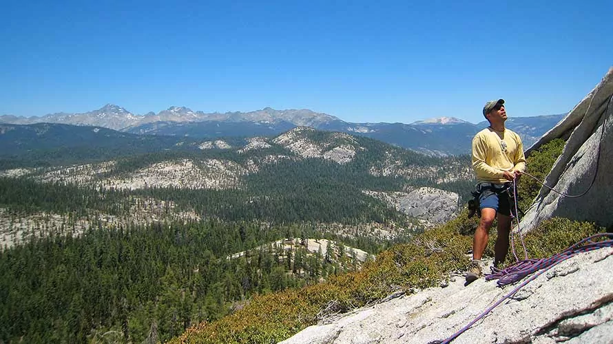 Rock climber belaying on the edge of a cliff at Fresno Dome, CA