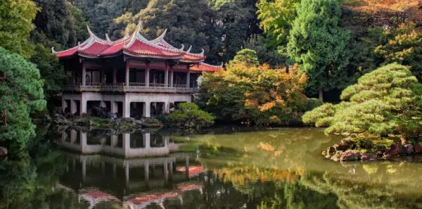 A traditional japanese building sits by the water in a tokyo park