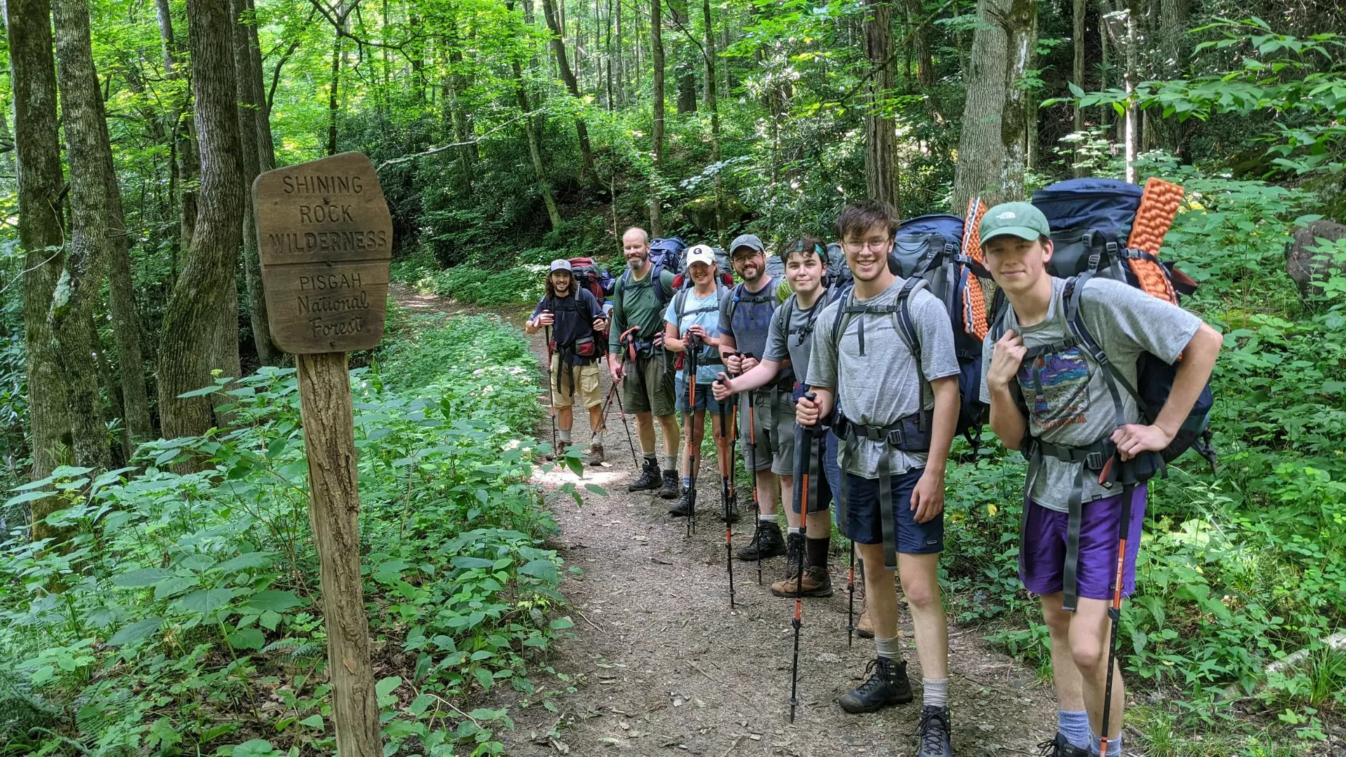 A group of backpackers pose near a Shining Rock Wilderness sign