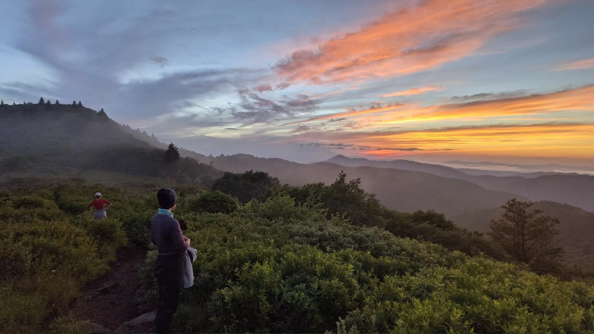 Hikers watch the sunrise from the top of a mountain