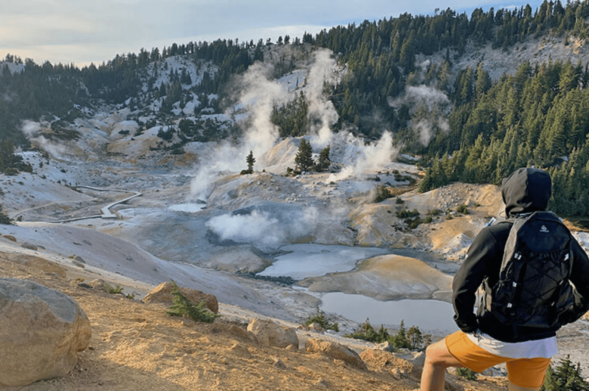 Lassen volcanic pools steam up as a hiker looks on.