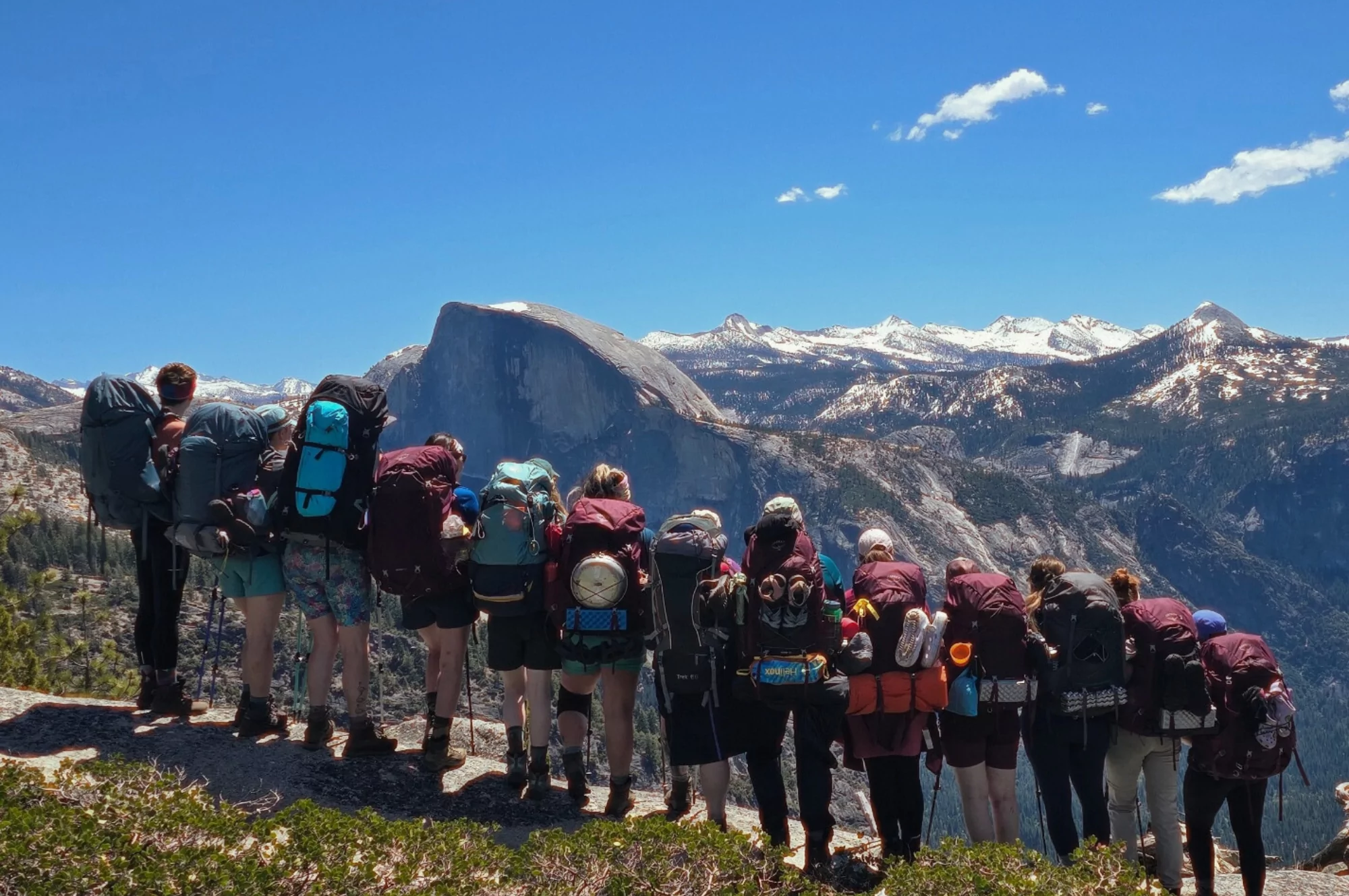 A group of hikers pose in front of an iconic Yosemite landscape