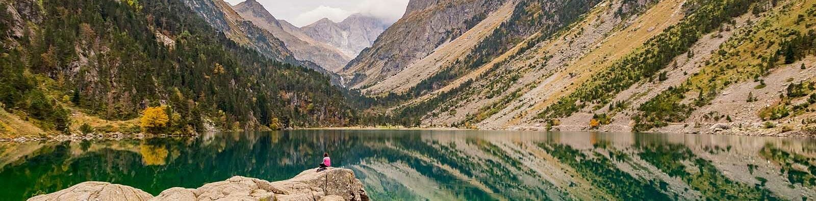 Lake in the Pyrenees with a woman sitting on a rock