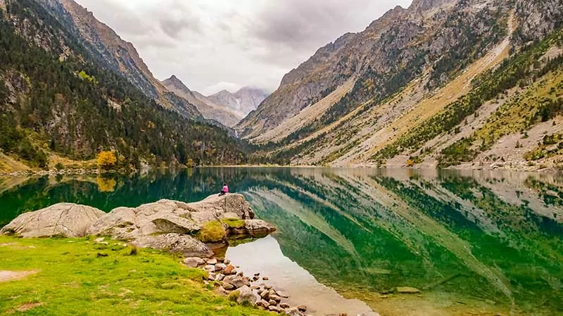 Cauterets, Hautes-Pyrénées, France - October 14, 2023: Lac de Gaube (Gaube Lake) with a loney woman sitting on a rock