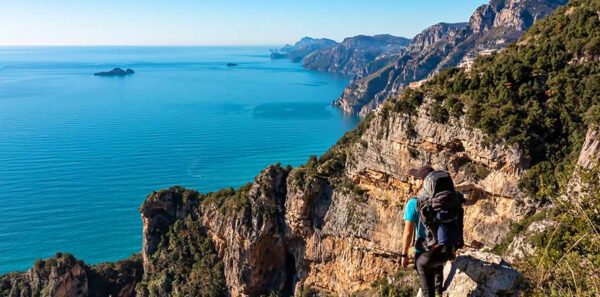 Man with panoramic view from hiking trail Path of Gods between coastal towns Positano and Praiano. Trekking in Lattari Mountains, Apennines, Amalfi Coast, Campania, Italy, Europe. Mediterranean Sea