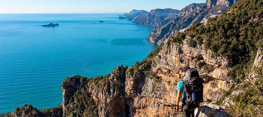 Man with panoramic view from hiking trail Path of Gods between coastal towns Positano and Praiano. Trekking in Lattari Mountains, Apennines, Amalfi Coast, Campania, Italy, Europe. Mediterranean Sea