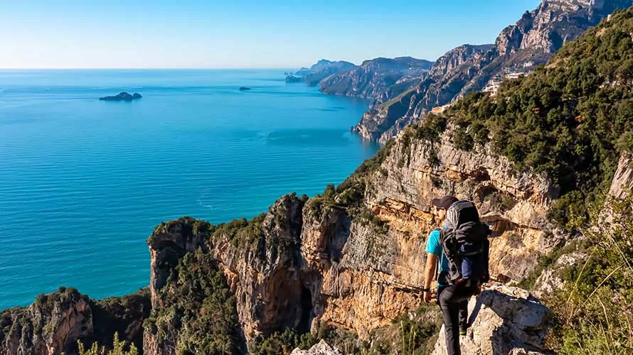 Man with panoramic view from hiking trail Path of Gods between coastal towns Positano and Praiano. Trekking in Lattari Mountains, Apennines, Amalfi Coast, Campania, Italy, Europe. Mediterranean Sea