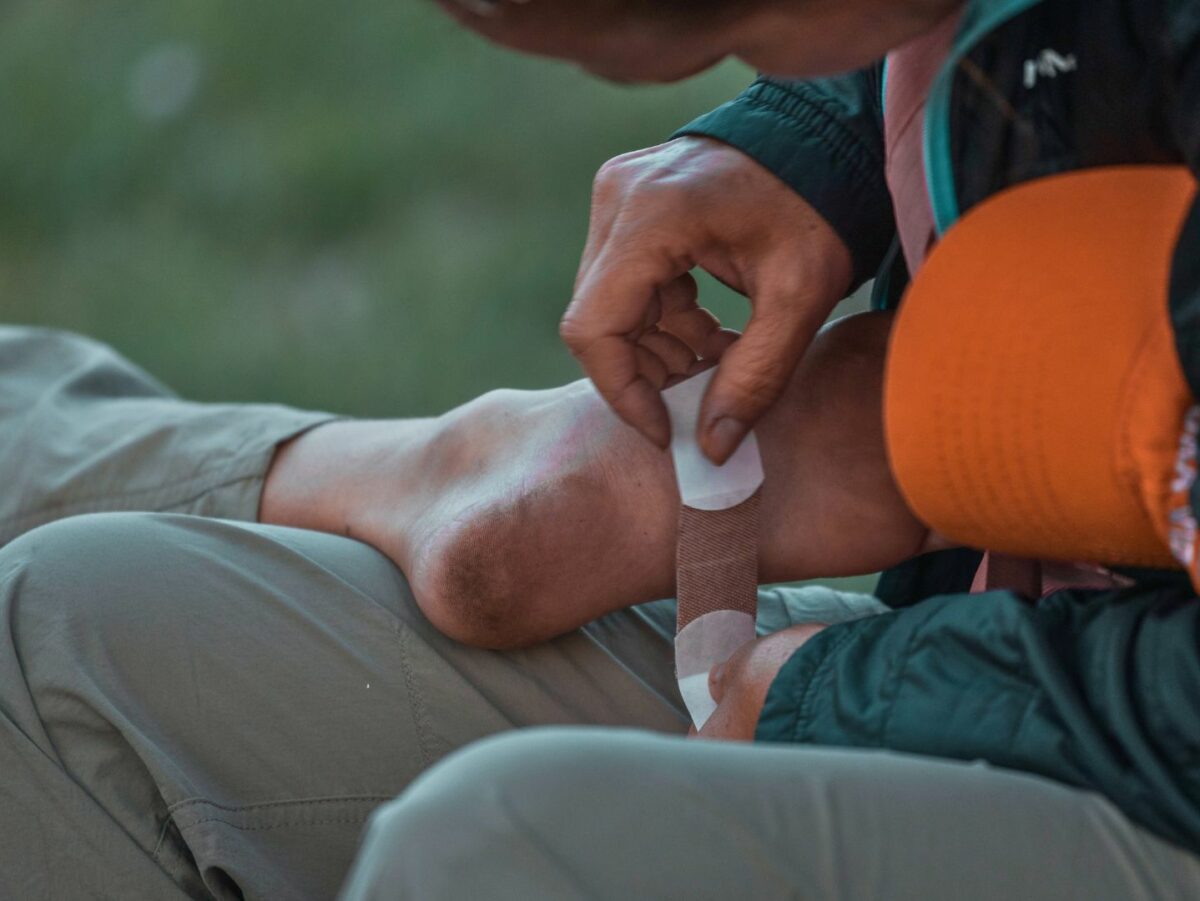 A hiking guide treats a blister on the bottom on someone's foot